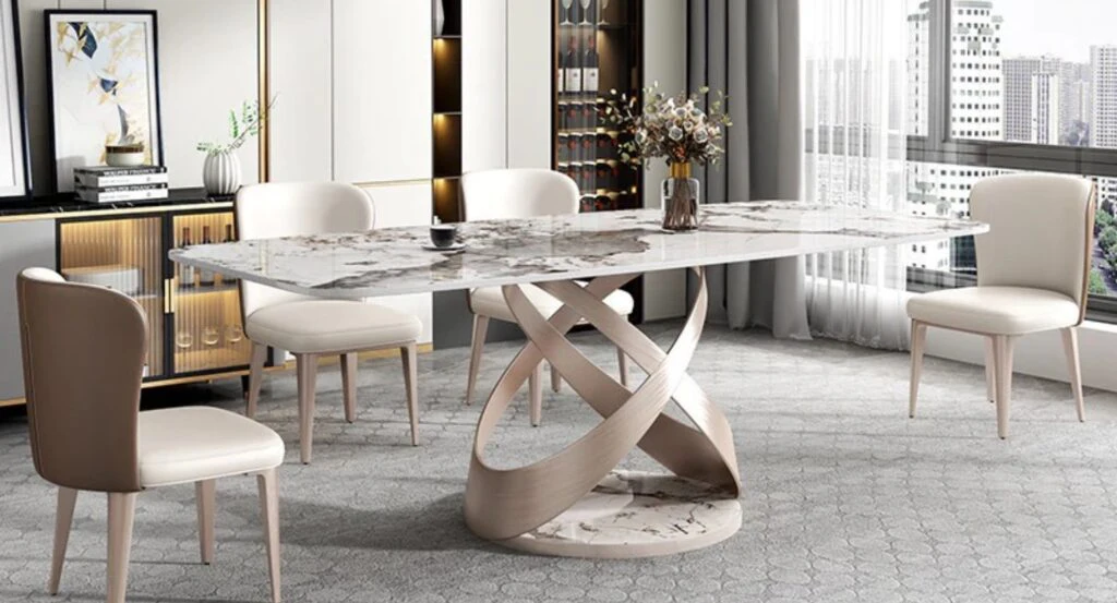 Eetkamer met marmeren tafel, beige stoelen en kastenwand met glas en verlichting.