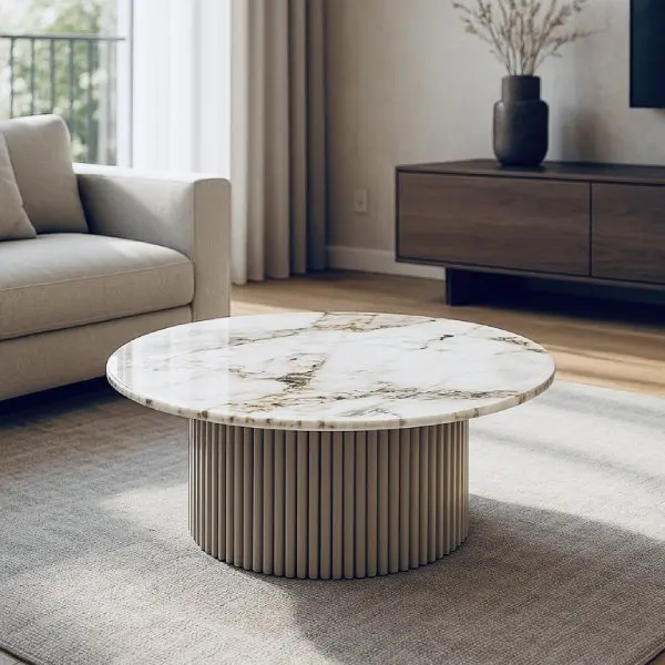 Ronde salontafel met marmeren blad en geribbelde beige basis in een lichte moderne woonkamer.