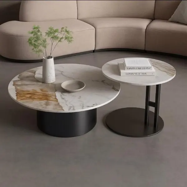 Twee ronde marmeren salontafels met zwarte poten in een moderne woonkamer met hoekbank.