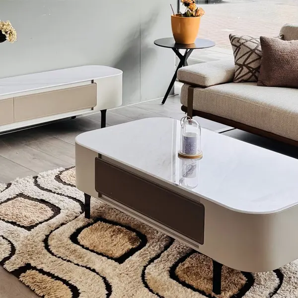 Rechthoekige salontafel met wit blad en zwarte poten in een eigentijdse woonkamer met beige bank.